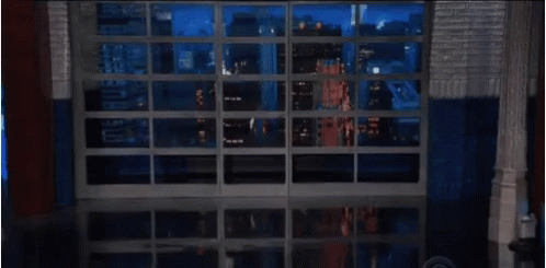 Man In Glasses And Suit Standing In Front Of Window GIF