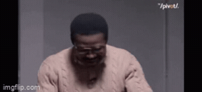 Man In Glasses And Sweater Laughing In Dark Room GIF
