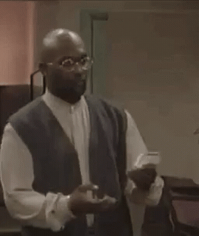 Man In Glasses And Vest Holding Something GIF