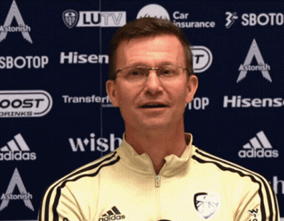 Man In Glasses And Yellow Adidas Shirt In Front Of Ad Wall For Hisen Sbotop And Wish GIF