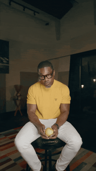 Man In Glasses And Yellow Shirt Holding Tennis Ball On Stool GIF