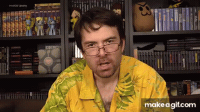 Man In Glasses And Yellow Shirt In Front Of Bookshelf Of Video Games GIF