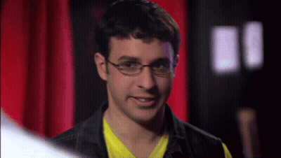 Man In Glasses And Yellow Smiling Before Red Curtain GIF