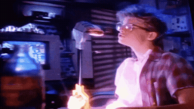Man In Glasses Holding Purple Object At Computer GIF
