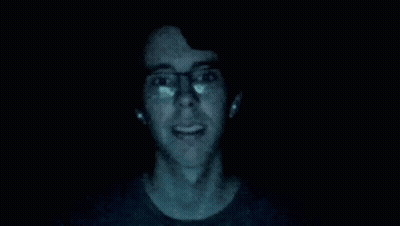 Man In Glasses Standing In Dark With Hands Up GIF