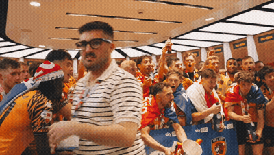 Man In Glasses Surrounded By Soccer Players And Fans GIF
