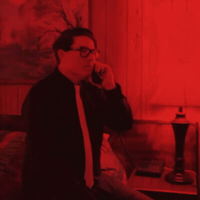 Man In Glasses Talking On Cell Phone In Red Room GIF