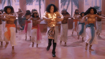 Man In Gold Outfit Dancing In Front Of Naked Women GIF