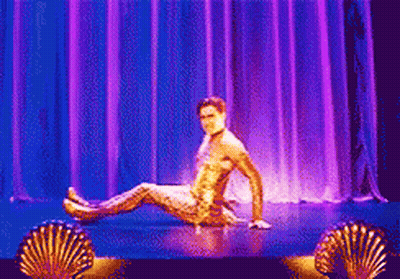 Man In Gold Outfit Sitting On Stage GIF