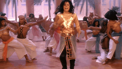 Man In Gold Outfit Stands In Front Of Group GIF