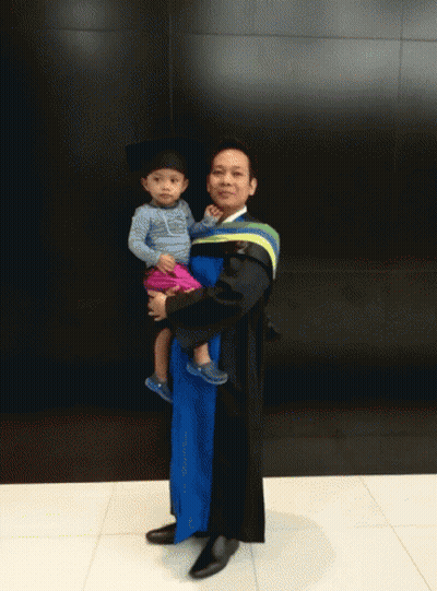 Man In Graduation Gown Holding Baby GIF