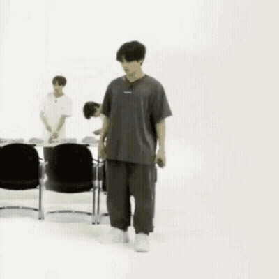 Man In Gray And Black Walking Past Chairs GIF