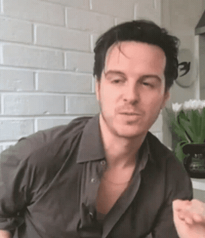 Man In Gray Shirt Making Funny Face At Brick Wall GIF