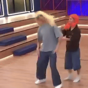 Man In Gray Shirt Next To Woman In Orange Hat GIF