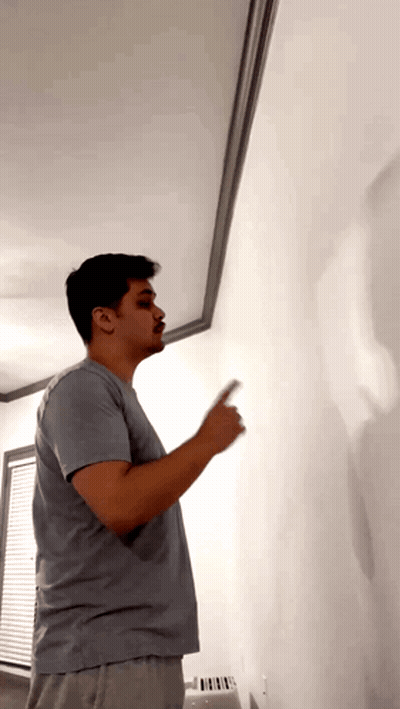 Man In Gray Shirt Pointing At White Wall GIF