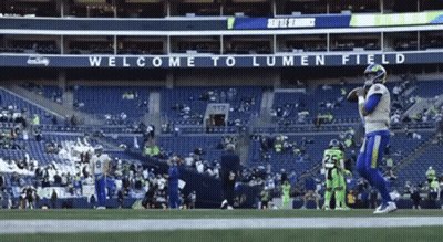 Man In Gray Shirt Talking To Man In Suit On Football Field GIF