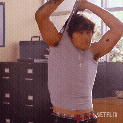 Man In Gray Tank Top Standing In Front Of Netflix Sign GIF
