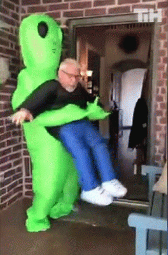 Man In Green Alien Costume Holding Another Man GIF