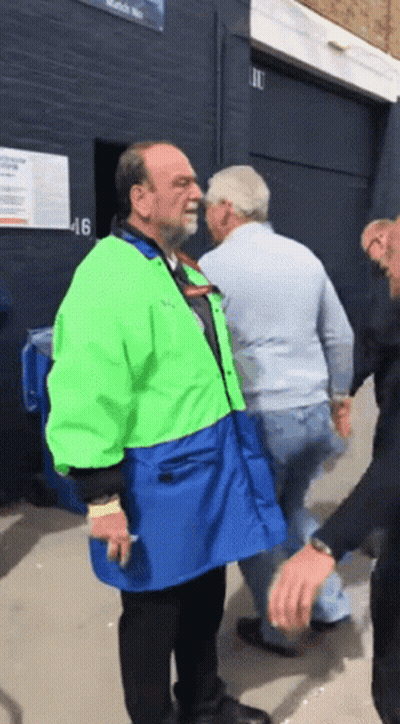 Man In Green And Blue Jacket Next To Another Man GIF