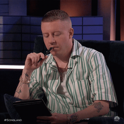 Man In Green And White Striped Shirt Holding Pen To Mouth GIF