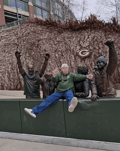 Man In Green Bay Packers Sweatshirt Sitting On Ledge GIF