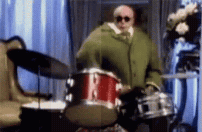 Man In Green Coat Playing Drum Set GIF
