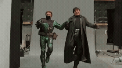 Man In Green Costume And Man In Black Coat Dancing GIF