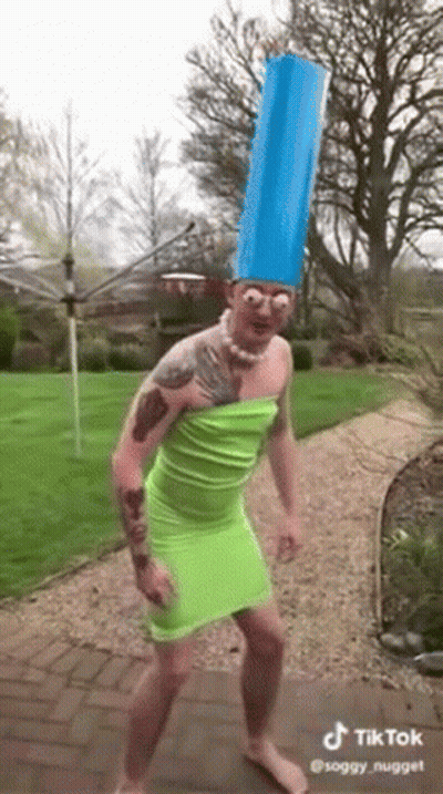 Man In Green Dress And Blue Hat Dancing In Garden GIF