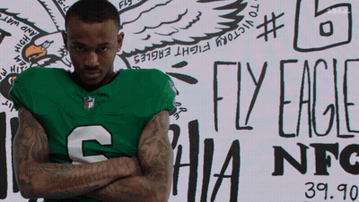 Man In Green Eagles Jersey In Front Of Fly Eagles Sign GIF