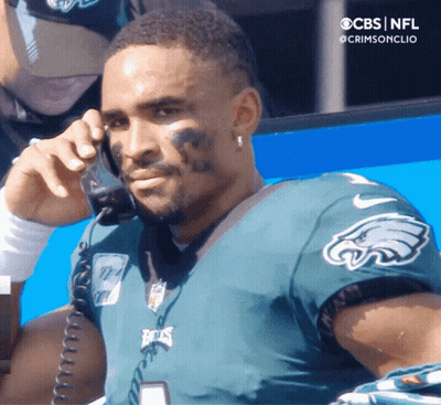 Man In Green Eagles Jersey Talking On Phone GIF