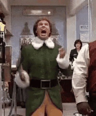 Man In Green Elf Costume Standing In Hallway GIF