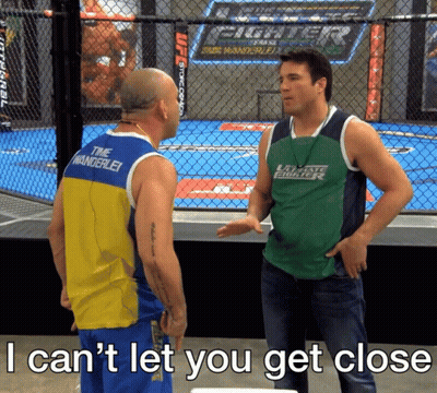 Man In Green Fighter Shirt Talking To Tank Top Man GIF