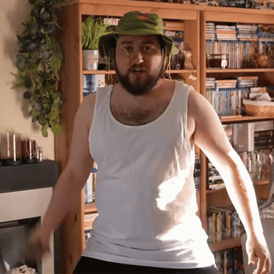 Man In Green Hat And White Tank Top By Bookshelf GIF