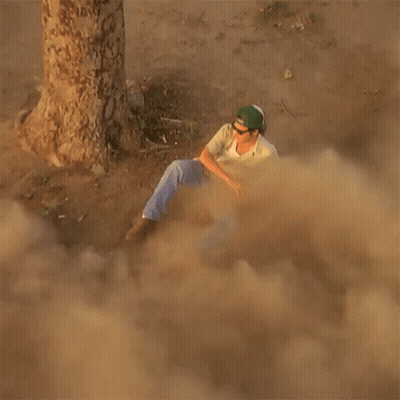 Man In Green Hat Sitting In Dust Near Tree GIF