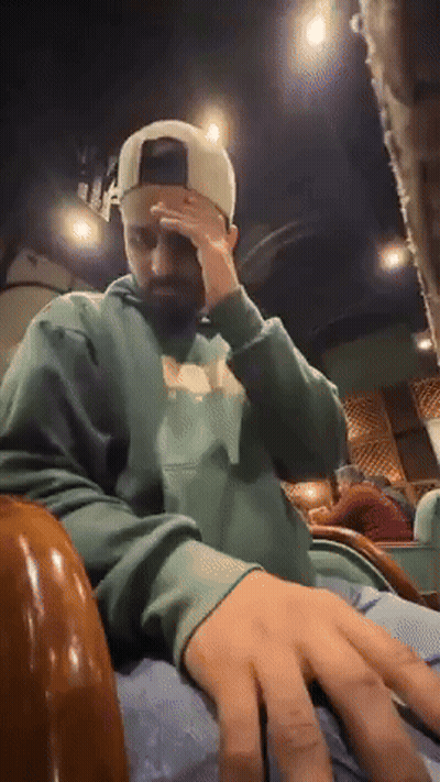 Man In Green Hoodie And White Hat Covering Face GIF