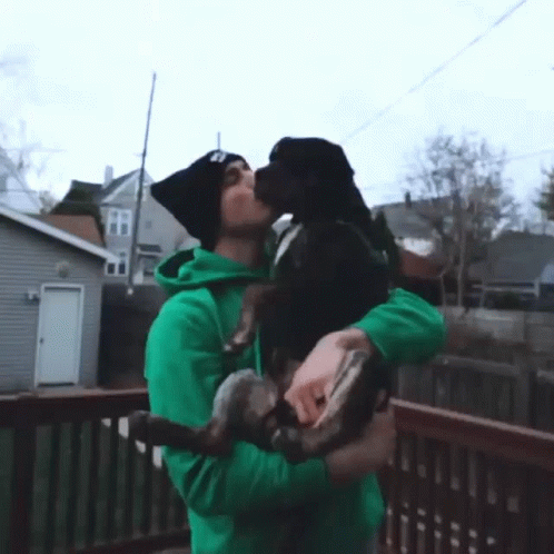 Man In Green Hoodie Kisses Dog On Nose GIF