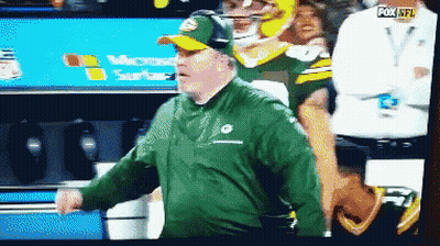 Man In Green Jacket And Hat In Front Of Fox NFL Sign GIF
