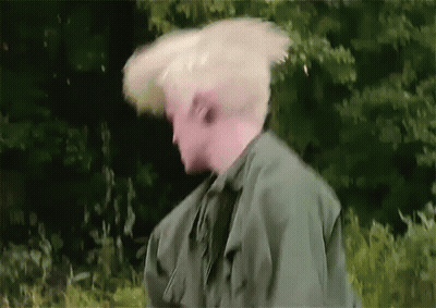 Man In Green Jacket Hair Blowing In Wind GIF