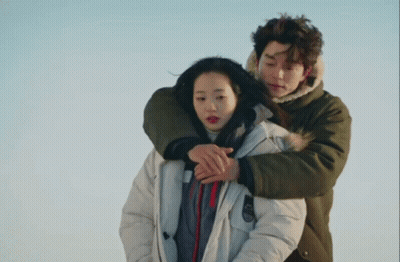 Man In Green Jacket Hugging Woman In White Parka GIF