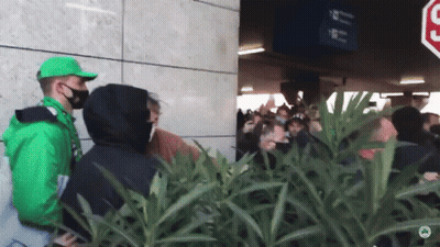 Man In Green Jacket In Front Of Crowd GIF