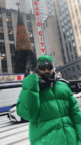 Man In Green Jacket In Front Of Radio City Building GIF