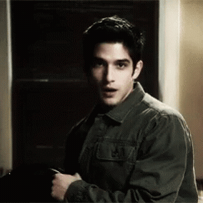 Man In Green Jacket Looking At Camera In Dark Room GIF