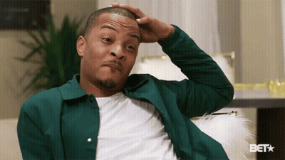 Man In Green Jacket Scratching Head On Couch GIF