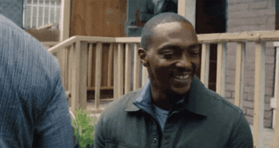 Man In Green Jacket Smiling Beside Wooden Fence GIF