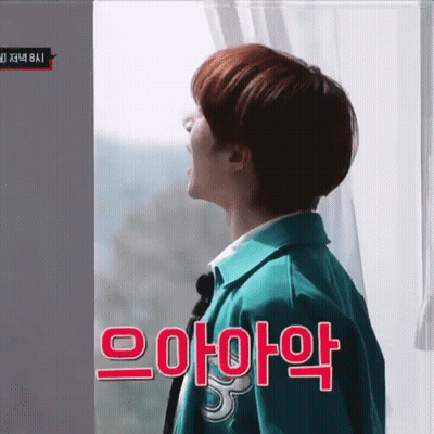Man In Green Jacket Standing In Front Of Window With Korean Writing GIF