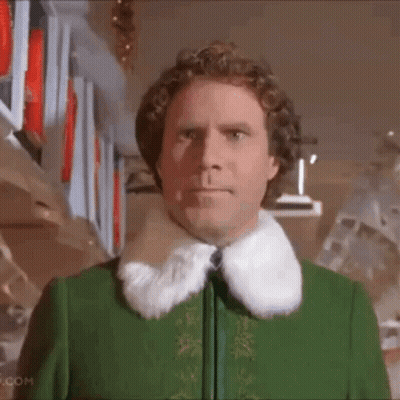 Man In Green Jacket With Fur Collar By Shelf GIF