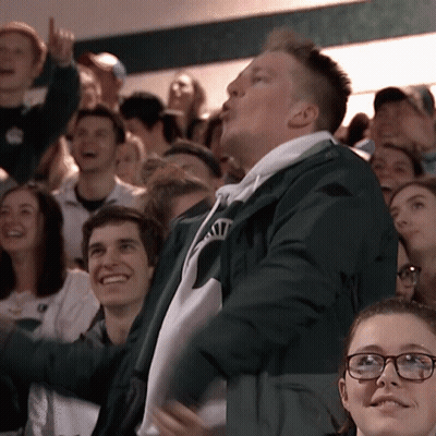 Man In Green Jacket With Letter N In Crowd GIF