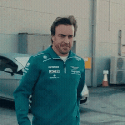 Man In Green Jacket With UCB Standing In Front Of Car GIF