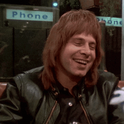 Man In Green Leather Jacket Smiling In Front Of Phone Booth GIF