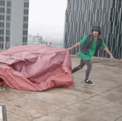 Man In Green Shirt And Black Hat Holding Red Tarp GIF
